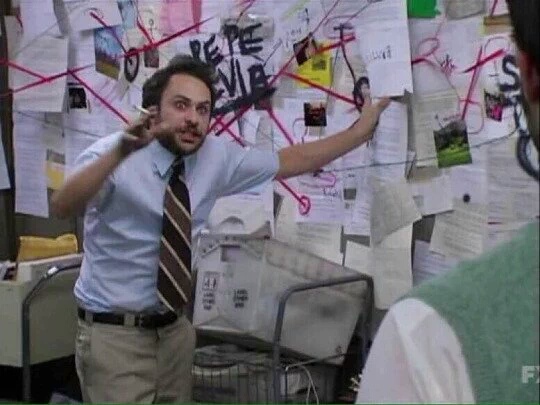 A wild-eyed, gesticulating man standing in front of a bulletin board covered with pieces of paper, connected by pins and a web of string